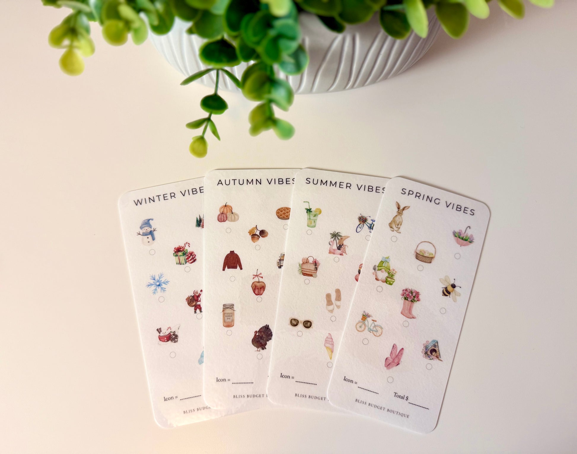 Four cards labeled 'Spring Vibes', 'Summer Vibes', 'Autumn Vibes', and 'Winter Vibes' with corresponding illustrations on a light surface. savings challenges