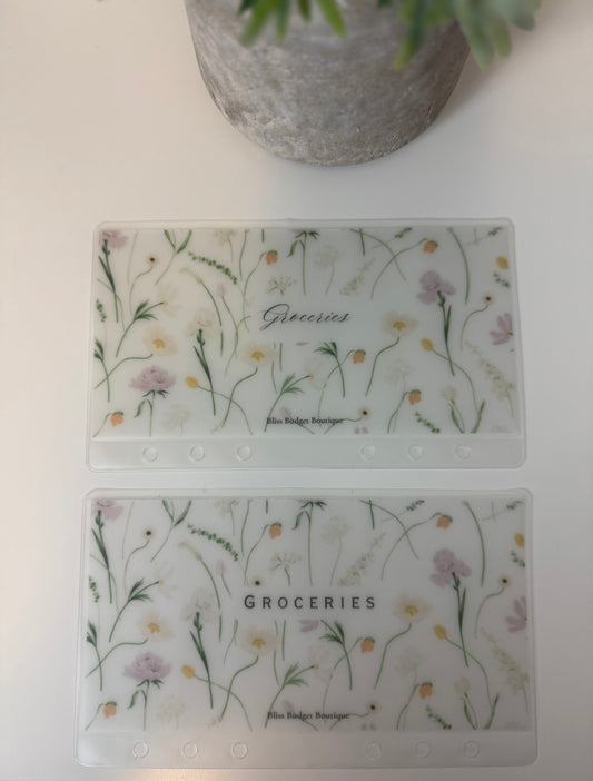 Two clear plastic cards with floral designs and 'Groceries' text on a white surface.
